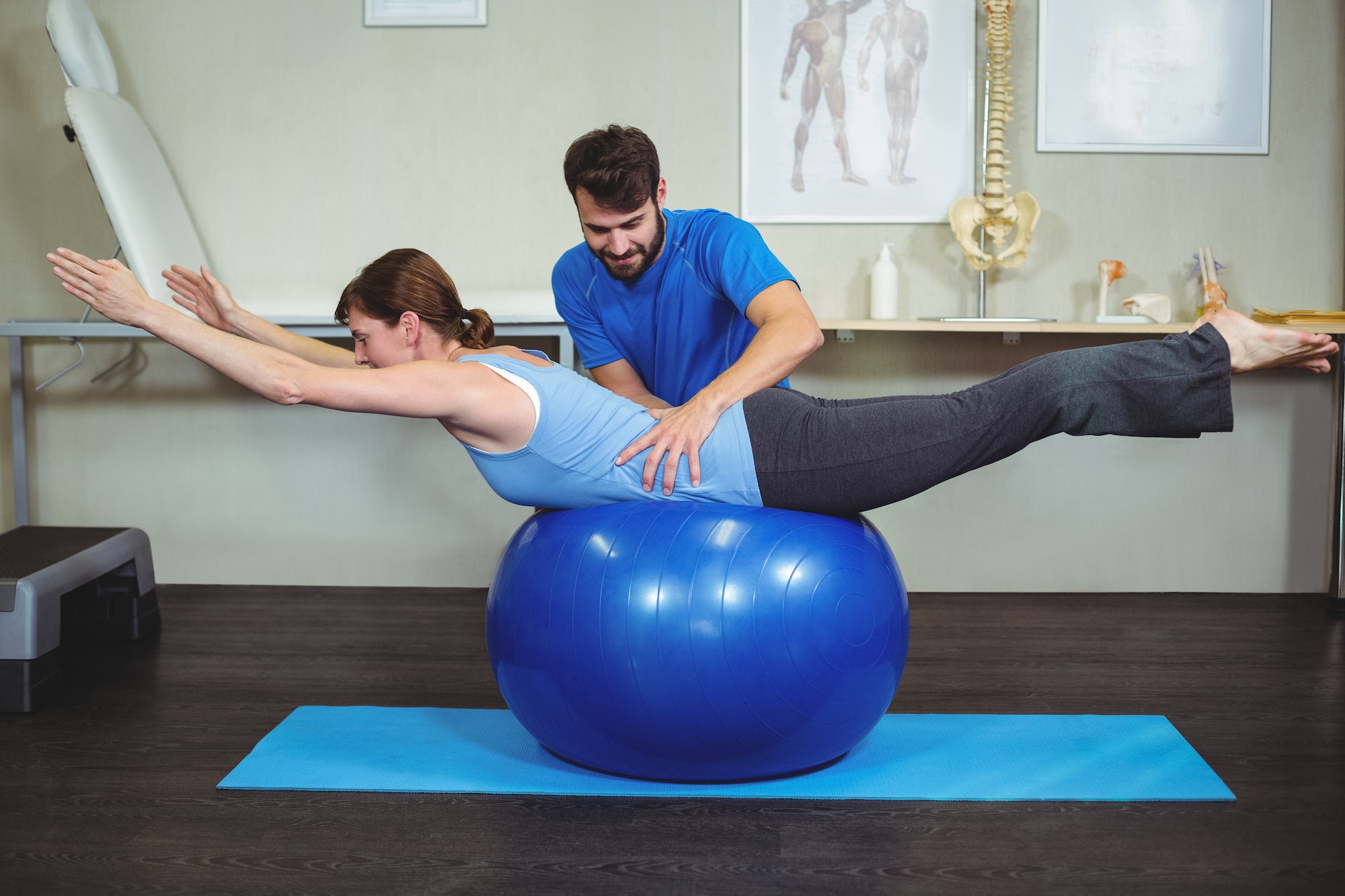 Physiotherapist assisting woman on exercise ball