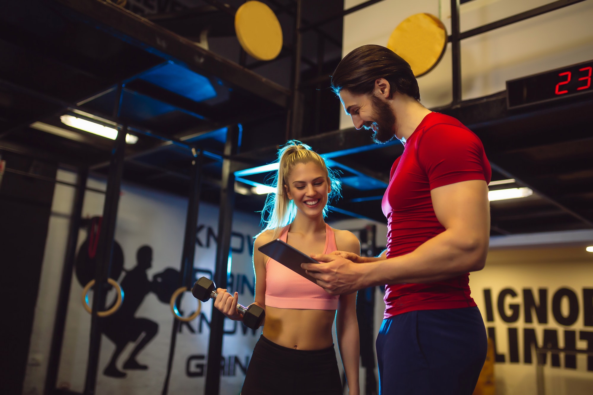 Smiling young woman with personal trainer in gym